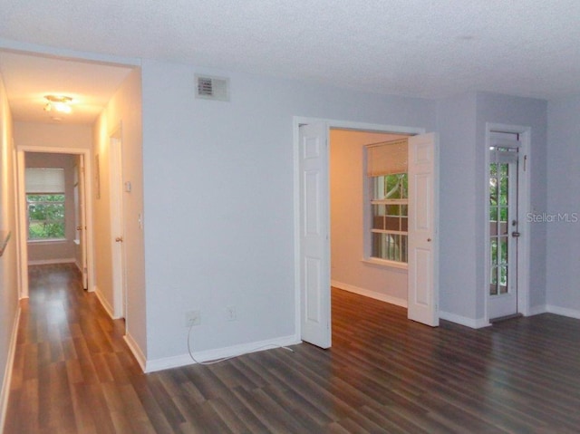 unfurnished room with a textured ceiling and dark hardwood / wood-style floors