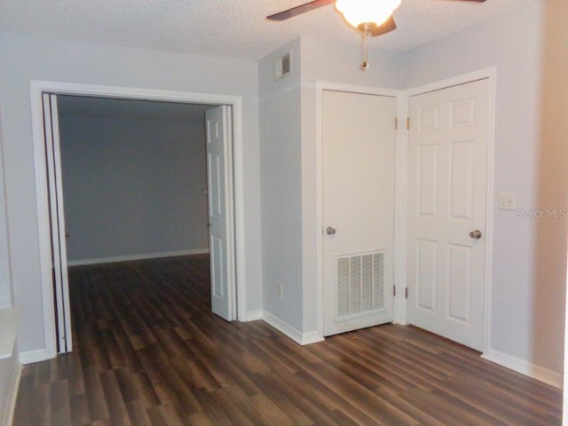 empty room featuring ceiling fan, a textured ceiling, and dark hardwood / wood-style flooring