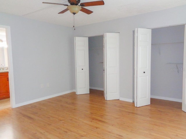 unfurnished bedroom featuring connected bathroom, ceiling fan, multiple closets, and light hardwood / wood-style flooring