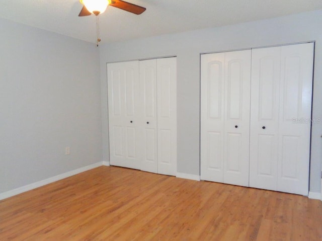 unfurnished bedroom with two closets, ceiling fan, and light wood-type flooring