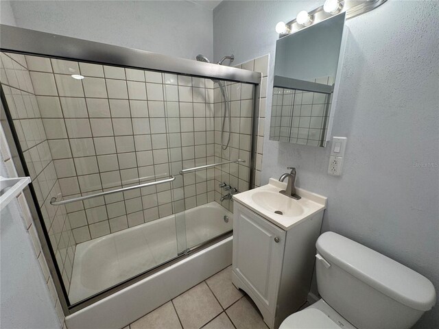 full bathroom featuring tile patterned floors, shower / bath combination with glass door, vanity, and toilet