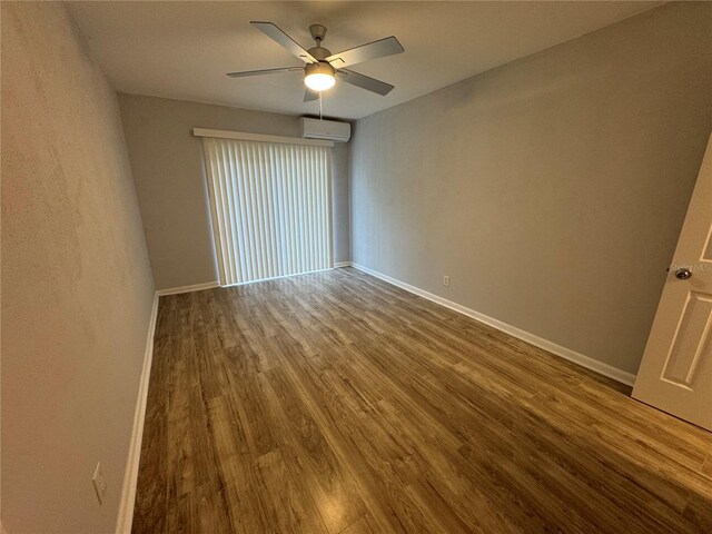 empty room featuring ceiling fan, wood-type flooring, and a wall mounted AC