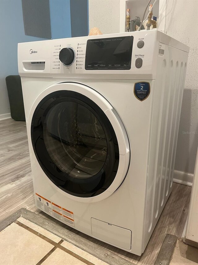 clothes washing area with washer / dryer and light hardwood / wood-style flooring