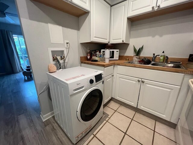 clothes washing area featuring cabinets, light wood-type flooring, sink, and washer / dryer