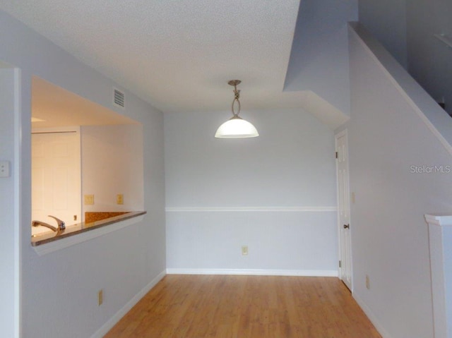 spare room with a textured ceiling and light wood-type flooring