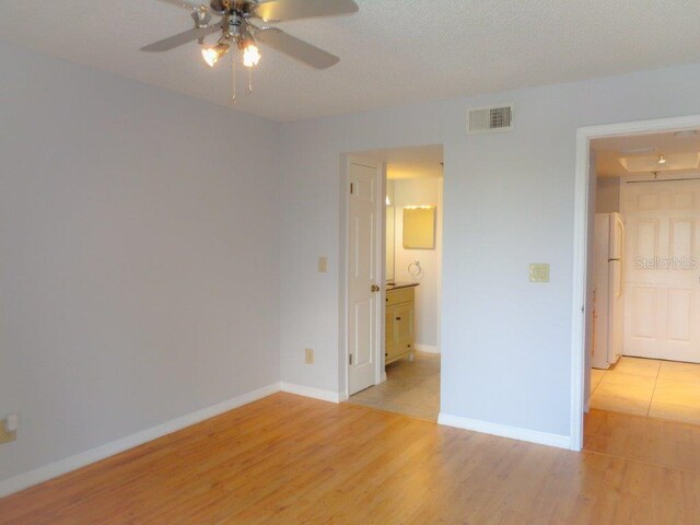 spare room with a textured ceiling, ceiling fan, and light wood-type flooring