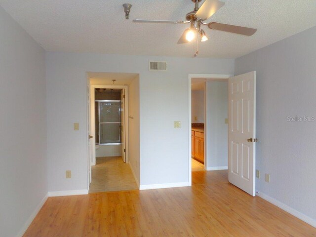 unfurnished room with a textured ceiling, ceiling fan, and light hardwood / wood-style flooring