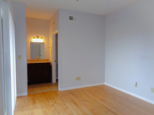 unfurnished bedroom with connected bathroom and light hardwood / wood-style floors