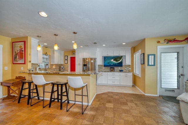 kitchen featuring white cabinets, stainless steel fridge with ice dispenser, light tile floors, and tasteful backsplash