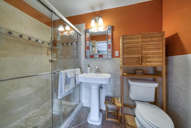 bathroom featuring a shower with shower door, tile walls, tile flooring, and toilet