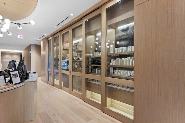 wine cellar with light hardwood / wood-style floors and a notable chandelier