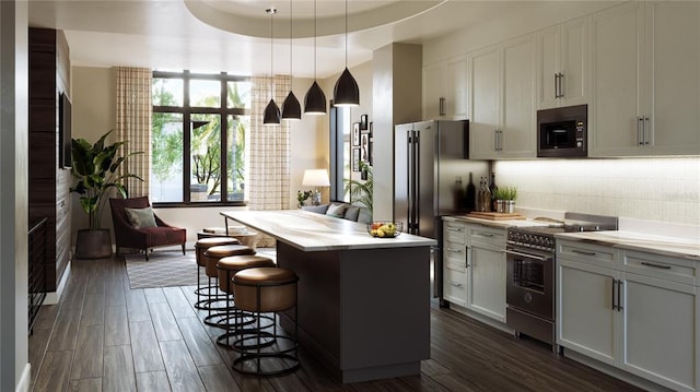 kitchen with hanging light fixtures, a tray ceiling, black microwave, a center island, and double oven range