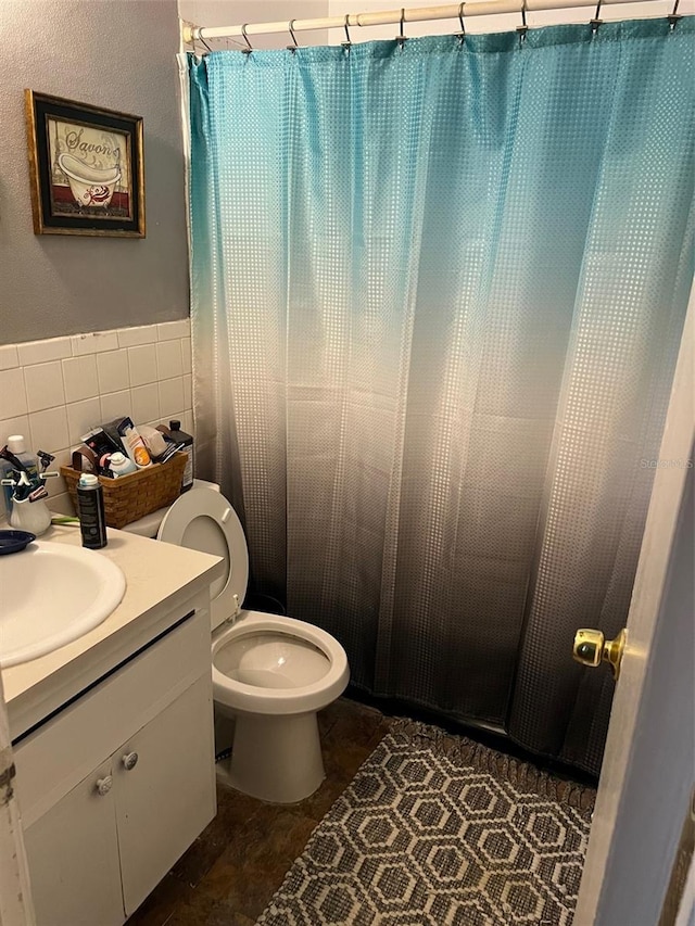 bathroom featuring curtained shower, tile walls, vanity, toilet, and tile patterned floors