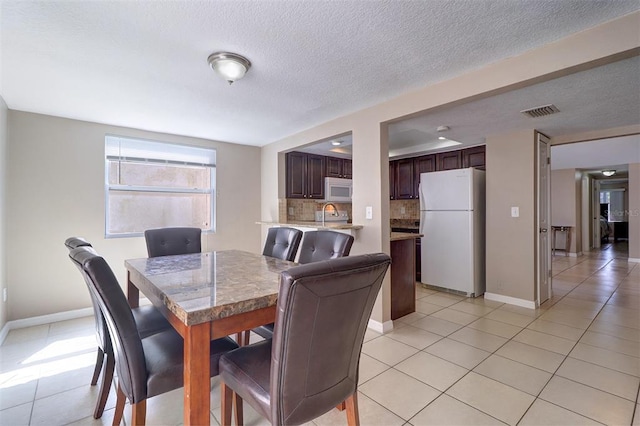 dining room featuring light tile floors, a textured ceiling, and sink