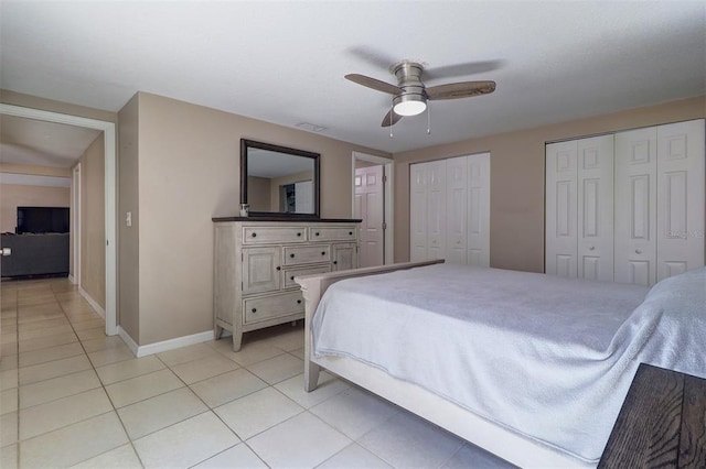 tiled bedroom featuring multiple closets and ceiling fan