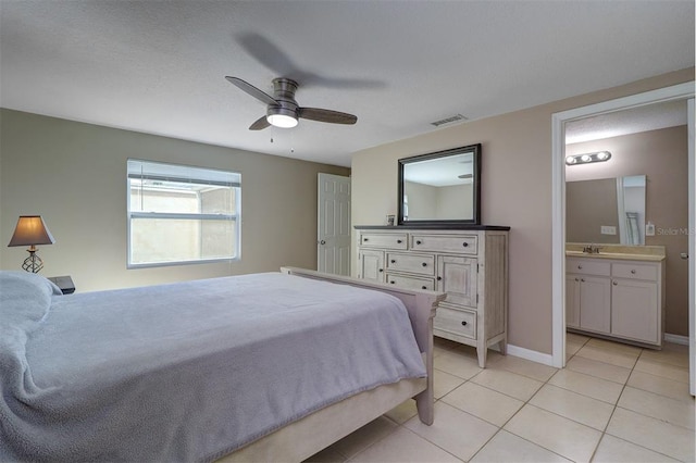 bedroom with connected bathroom, light tile flooring, ceiling fan, and sink