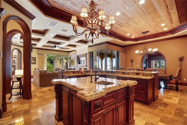 kitchen with pendant lighting, sink, crown molding, and an island with sink