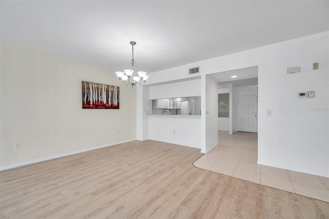 unfurnished living room with light hardwood / wood-style floors and an inviting chandelier