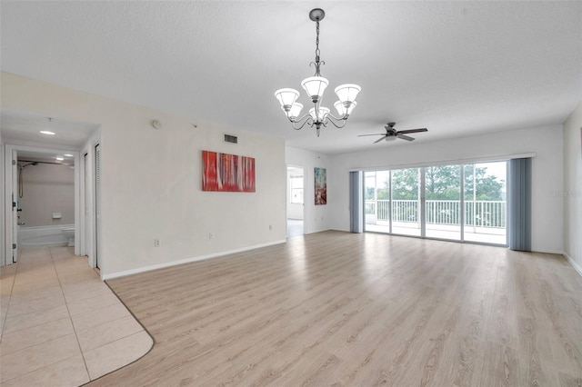 unfurnished room with a textured ceiling, light tile floors, and ceiling fan with notable chandelier