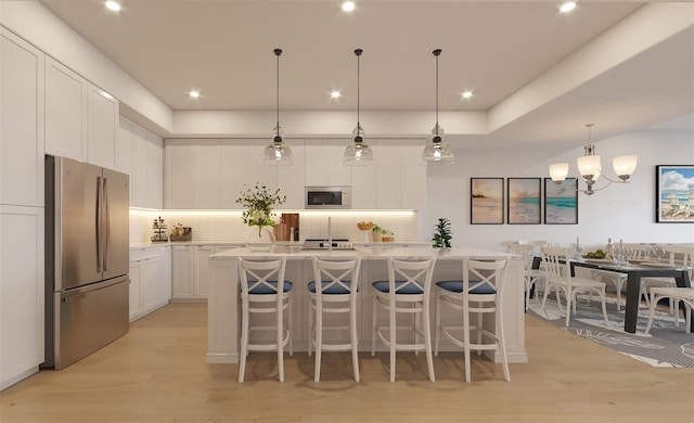 kitchen featuring a kitchen island with sink, built in microwave, stainless steel fridge, and white cabinetry