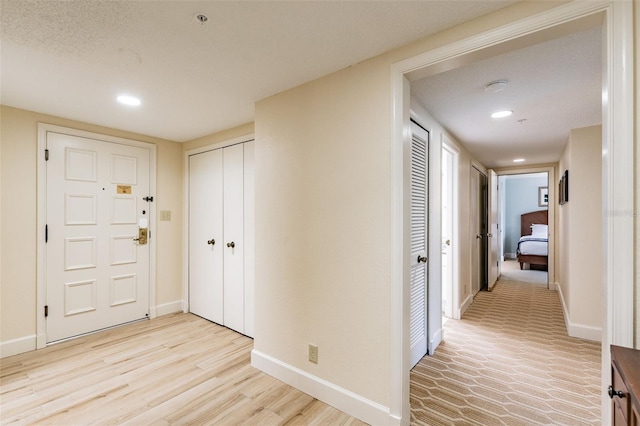 hallway with light wood finished floors, baseboards, and recessed lighting