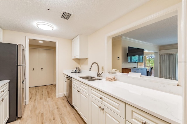 kitchen featuring stainless steel appliances, a sink, visible vents, light wood-style floors, and white cabinets