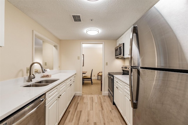 kitchen featuring white cabinets, visible vents, stainless steel appliances, and a sink