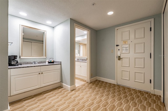 bathroom featuring recessed lighting, baseboards, a textured ceiling, and vanity