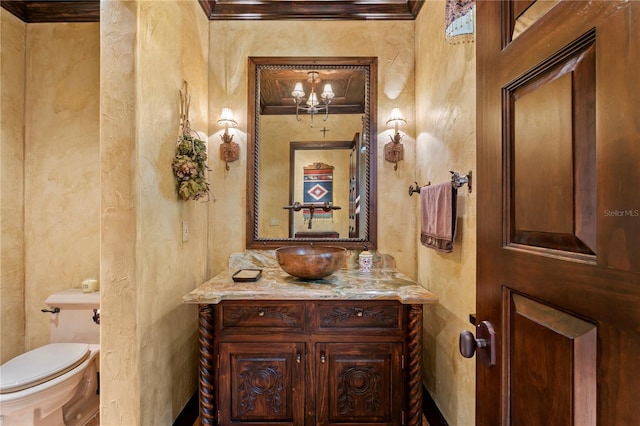 bathroom with toilet, an inviting chandelier, and vanity