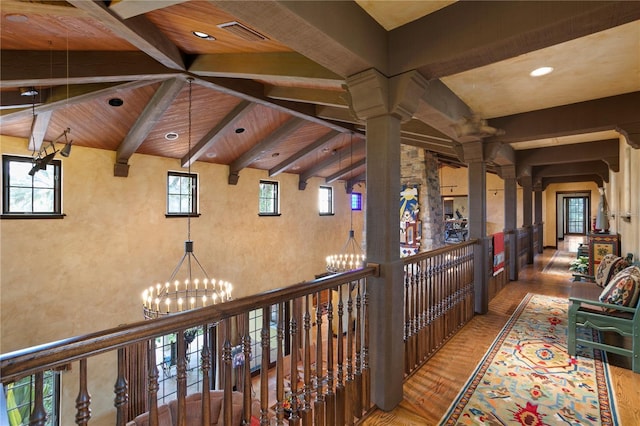 hallway with a notable chandelier, beamed ceiling, hardwood / wood-style flooring, wooden ceiling, and decorative columns