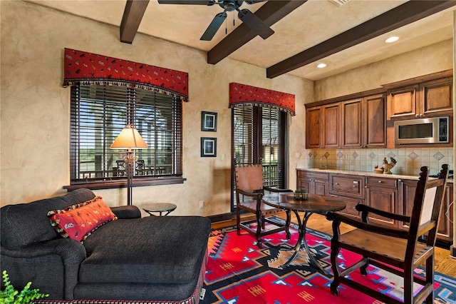 living area featuring ceiling fan, beamed ceiling, and hardwood / wood-style floors