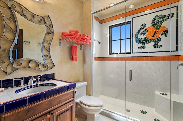 bathroom featuring toilet, a shower with door, and vanity