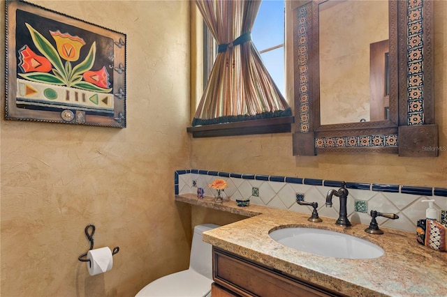 bathroom featuring toilet, vanity, and tasteful backsplash