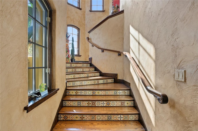 stairs with a wealth of natural light and a high ceiling