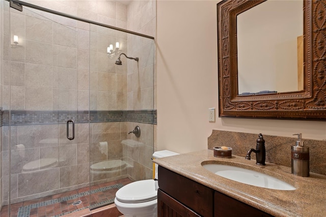 bathroom featuring toilet, vanity, and a shower with shower door