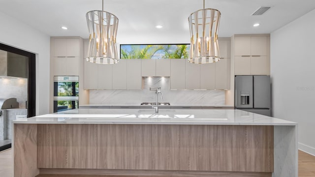 kitchen with visible vents, modern cabinets, appliances with stainless steel finishes, and tasteful backsplash