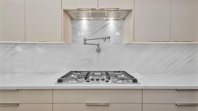 kitchen with stainless steel gas stovetop, wall chimney range hood, and modern cabinets