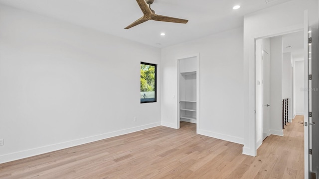 unfurnished bedroom with recessed lighting, a ceiling fan, baseboards, light wood finished floors, and a walk in closet