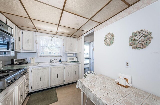 kitchen with a drop ceiling, sink, tile countertops, and stainless steel appliances