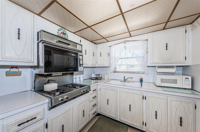 kitchen with white cabinetry, sink, a paneled ceiling, and stainless steel gas cooktop