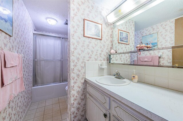 full bathroom with toilet, a textured ceiling, vanity, enclosed tub / shower combo, and tile patterned flooring