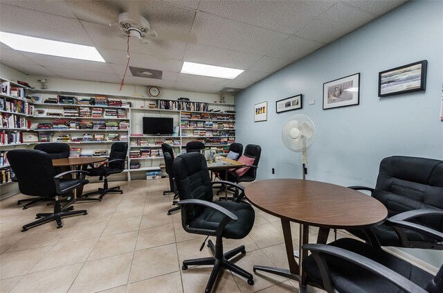 tiled office space featuring a paneled ceiling and ceiling fan