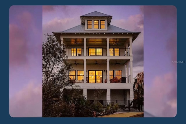 back house at dusk featuring a balcony and ceiling fan