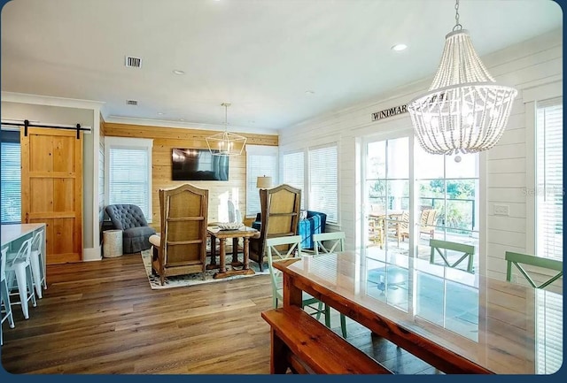 dining area featuring an inviting chandelier, hardwood / wood-style flooring, crown molding, and a barn door