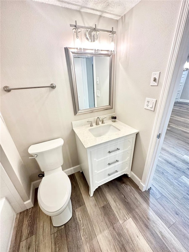 bathroom featuring vanity, a textured ceiling, toilet, and hardwood / wood-style flooring