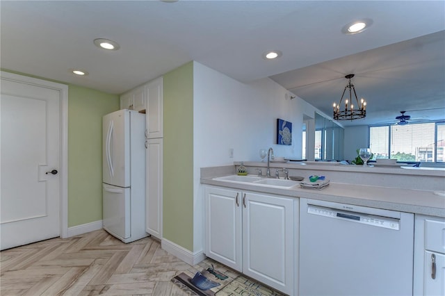 kitchen with white appliances, sink, white cabinets, light parquet flooring, and decorative light fixtures