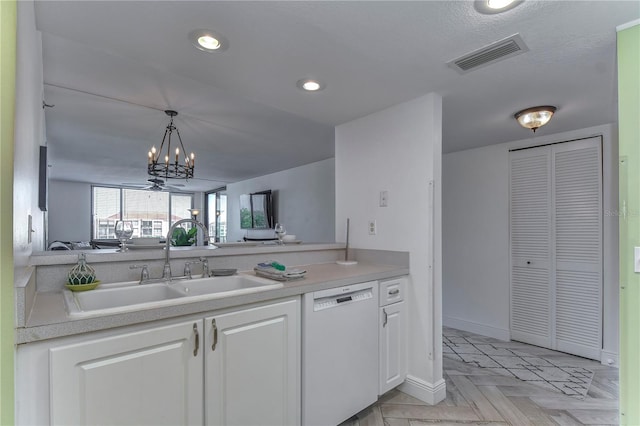 kitchen featuring white dishwasher, light parquet floors, white cabinets, hanging light fixtures, and an inviting chandelier