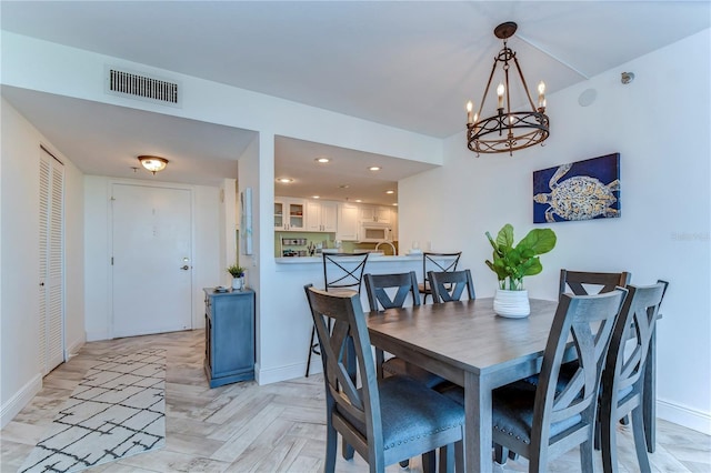 dining area with light parquet floors and a notable chandelier