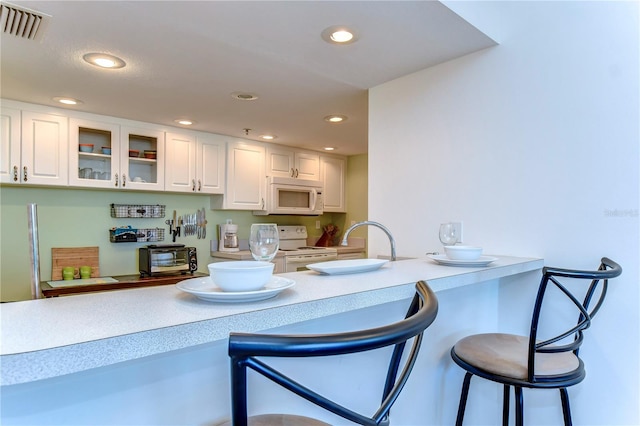 kitchen with white cabinets, white appliances, and a breakfast bar