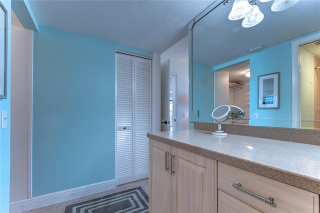 bathroom with a textured ceiling and vanity with extensive cabinet space